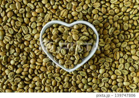 Green coffee beans in heart shaped bowl on coffee bean background Green coffee beans in heart shaped bowl on coffee bean background 139747806