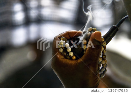 Hand holding a rosary and a pipe Hand holding a rosary and a pipe 139747986