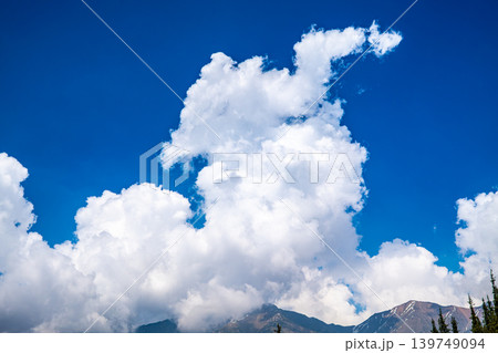 Dramatic white cumulus clouds over snow capped Tian Shan mountains and blue sky Dramatic white cumulus clouds over snow capped Tian Shan mountains and blue sky 139749094