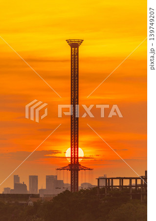 Towering amusement ride silhouette against a vibrant sunset sky Towering amusement ride silhouette against a vibrant sunset sky 139749207