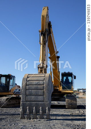 Excavator bucket closeup at construction site against clear blue sky Excavator bucket closeup at construction site against clear blue sky 139749853