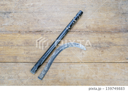 Old Worn Broken Iron Sickle Blade Separated From Its Black Metal Handle Lying Flat on a Rustic Weathered Wooden Plank Surface Showing Clear Break Point Old Worn Broken Iron Sickle Blade Separated From Its Black Metal Handle Lying Flat on a Rustic Weathered Wooden Plank Surface Showing Clear Break Point 139749883