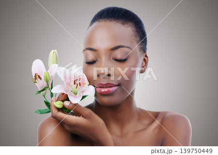 Eyes closed, flowers and black woman with shine, grooming and treatment on grey studio background. African person, girl and model with organic cosmetics and beauty with skincare, glow and aesthetic Eyes closed, flowers and black woman with shine, grooming and treatment on grey studio background. African person, girl and model with organic cosmetics and beauty with skincare, glow and aesthetic 139750449