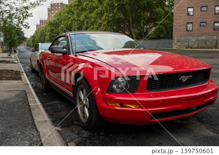 New york, usa august 18,2024. Red ford mustang convertible parked on a harlem street, surrounded by urban brownstones, green trees and summer city life 139750601