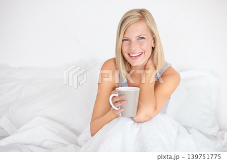 Woman, portrait and drinking coffee in bed for morning relax or home beverage for comfort, peace or happy. Female person, face and smile with mug on duvet for warm caffeine or vacation, rest or tea 139751775