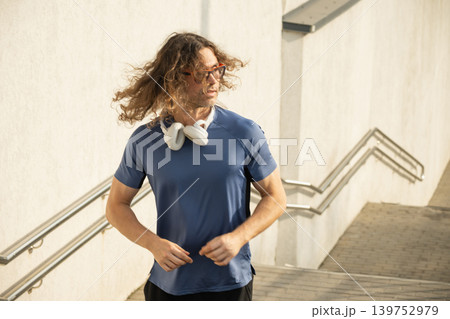 Long hair runner in sunlight near city stairs Long hair runner in sunlight near city stairs 139752979