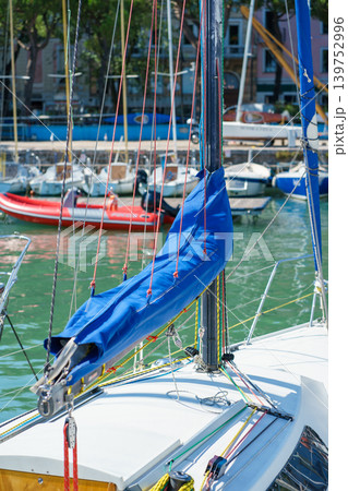 Detailed view of sailboat mast, ropes and blue sail cover, showcasing nautical equipment, sailing lifestyle and technical rigging elements Detailed view of sailboat mast, ropes and blue sail cover, showcasing nautical equipment, sailing lifestyle and technical rigging elements 139752996