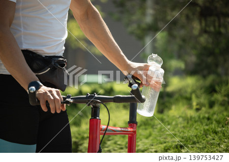 Man Relaxing with Water Bottle After Cycling. Man Relaxing with Water Bottle After Cycling. 139753427