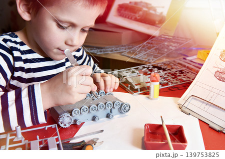 Little boy collects plastic model tank Little boy collects plastic model tank 139753825