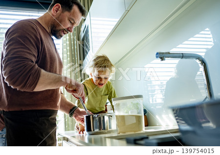 Dad and toddler preparing simple meal together in bright kitchen. 139754015