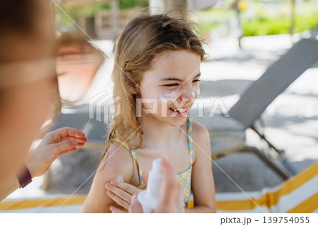 Mother applying sunscreen on daughters face. Mother applying sunscreen on daughters face. 139754055