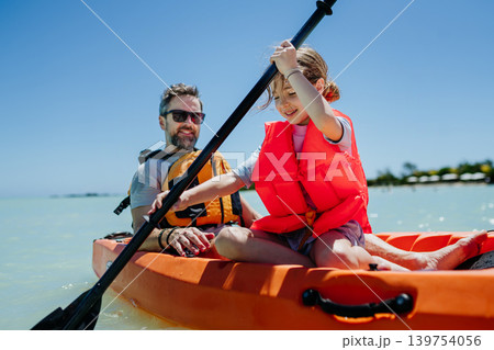 Father kayaking with daughter on calm sea during family summer vacation. 139754056