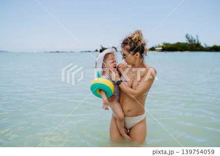 Mother holding cying daughter, standin in sea water. 139754059