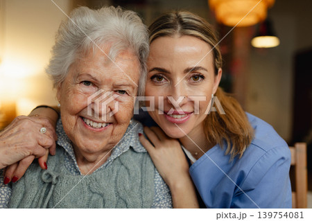 Portrait of caring healthcare worker visiting a senior patient at home, hugging her. 139754081