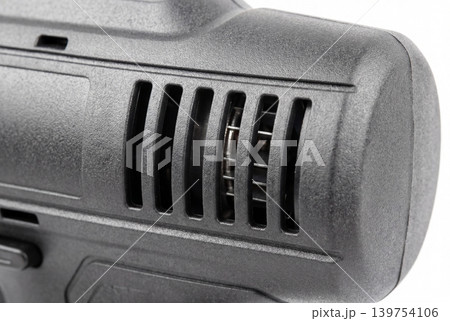 Macro photo of a black power tool housing with ventilation slots and visible motor detail, isolated on white background. Ideal for repair, engineering, hardware, and industrial equipment concepts. 139754106