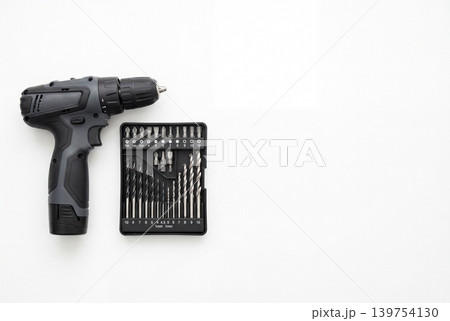 Top view of a cordless drill and drill bit set isolated on white background. Practical power tool kit for repair, installation, construction, furniture assembly, workshop, and DIY tasks. Top view of a cordless drill and drill bit set isolated on white background. Practical power tool kit for repair, installation, construction, furniture assembly, workshop, and DIY tasks. 139754130