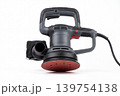 Powerful random orbital sander with sanding pad and dust bag isolated on white background. Electric tool for woodworking, surface finishing, renovation, repair, polishing and workshop tasks. 139754138