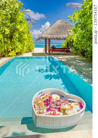 Stunning couple honeymoon luxury resort swimming pool floating breakfast tray morning sunlight scenic tropical paradise romantic vacation destination dreamy luminous ethereal serene exotic famous 139754167