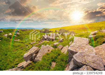 sunset over mountainous landscape during summertime. boulders and rock formations surrounded grassy hills. picture of an untouched highland. leadership corporate wallpaper under the rainbow 139754249