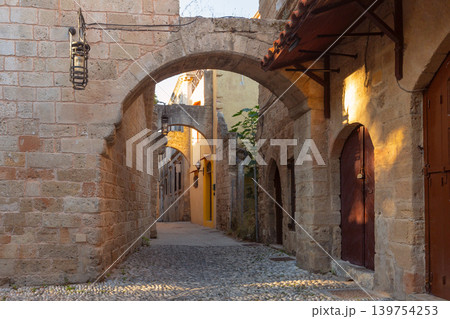 Narrow cobblestone street with stone arches in Rhodes Old Town Greece Narrow cobblestone street with stone arches in Rhodes Old Town Greece 139754253