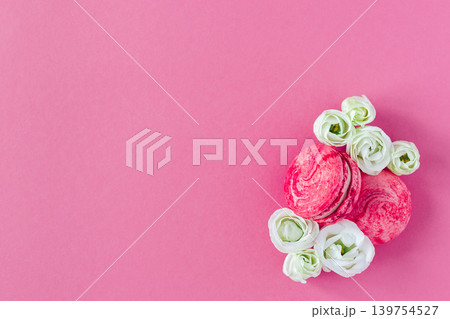 Two pink French macarons with white flowers. Flat lay, place for text. Two pink French macarons with white flowers. Flat lay, place for text. 139754527