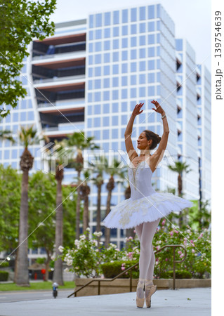 Ballerina on pointe in urban plaza with modern glass buildings 139754639