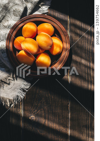 Ripe apricots in a ceramic bowl on the wooden table. Ripe apricots in a ceramic bowl on the wooden table. 139754662