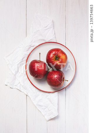 Three red ripe apples on a plate. Top view on a wooden table. 139754663