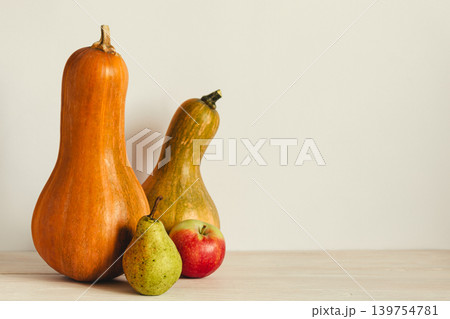 Two ripe organic pumpkin, pear and apple on a pastel beige background. Minimal eco concept for Thanksgiving card or background. Two ripe organic pumpkin, pear and apple on a pastel beige background. Minimal eco concept for Thanksgiving card or background. 139754781