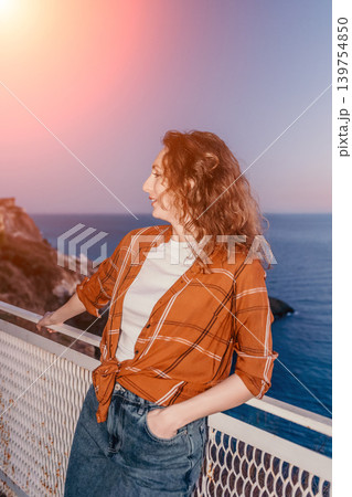 Woman sunset coast young woman enjoying the peaceful mediterranean breeze while standing on a balcony at golden hour Woman sunset coast young woman enjoying the peaceful mediterranean breeze while standing on a balcony at golden hour 139754850