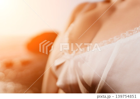 Lingerie sunset beach close up of woman wearing delicate white lace during golden hour for romantic summer vacation and relaxation Lingerie sunset beach close up of woman wearing delicate white lace during golden hour for romantic summer vacation and relaxation 139754851
