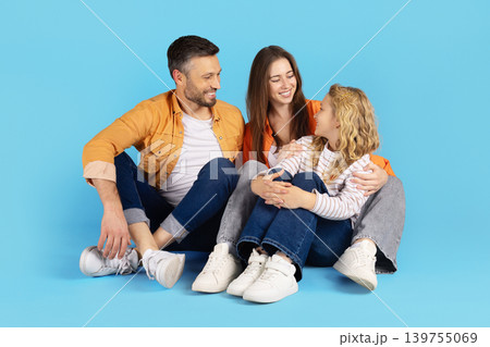 Caucasian parents and daughter sitting together on blue studio background 139755069