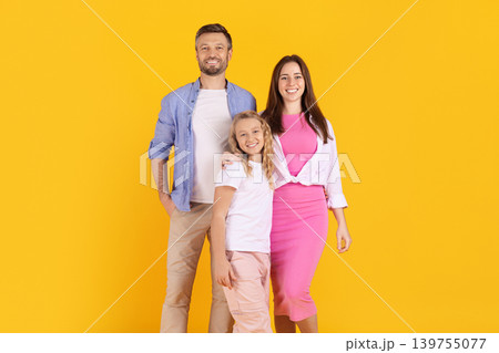 Cheerful caucasian family of three smiling together on yellow studio background Cheerful caucasian family of three smiling together on yellow studio background 139755077