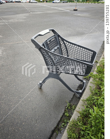 Abandoned grey shopping cart left alone on wet asphalt in an empty parking 139755281