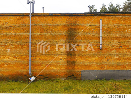 Weathered wall with moss and fixtures. Functional scene of mossy stained wall with pipes and bricks 139756114