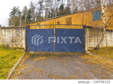 Hidden entrance with vivid contrast. Concealed compound entry with textured surfaces and autumn decor 139756115