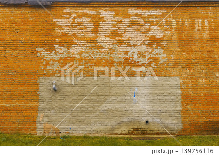 Worn brick with peeling paint. Faded orange brick surface showing signs of neglect and deterioration 139756116