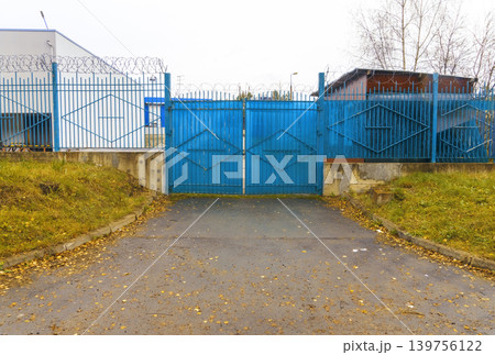 Decorative steel gate with lock. Enclosed driveway with decorative diamond pattern and locked gate 139756122