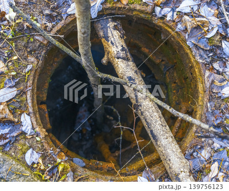Decayed circular opening amid silent woods. Forgotten well with moss and rust in dense forest 139756123