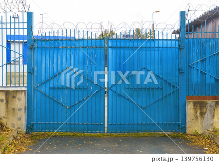 Weathered gate with rusted hinges. Industrial gate showing signs of decay and urban abandonment 139756130