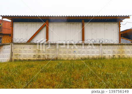 Industrial security visuals. Durable security structure featuring barbed wire and weathered surfaces Industrial security visuals. Durable security structure featuring barbed wire and weathered surfaces 139756149