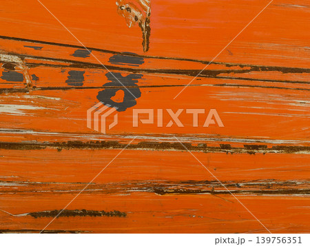 Macro texture of weathered orange paint on a wooden surface. Abstract background with deep cracks, scratches, and visible wood grain through peeling paint layers. Wooden fence or flooring. Macro texture of weathered orange paint on a wooden surface. Abstract background with deep cracks, scratches, and visible wood grain through peeling paint layers. Wooden fence or flooring. 139756351