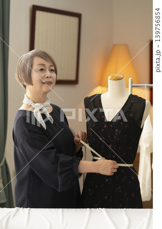 シニア女性のデザイナーがアトリエで洋服を作る シニア女性のデザイナーがアトリエで洋服を作る 139756854