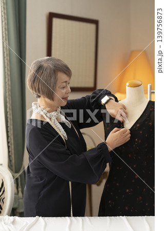 シニア女性のデザイナーがアトリエで洋服を作る シニア女性のデザイナーがアトリエで洋服を作る 139756873