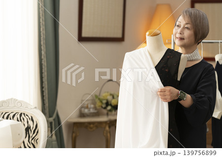 シニア女性のデザイナーがアトリエで洋服を作る シニア女性のデザイナーがアトリエで洋服を作る 139756899