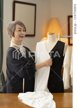 シニア女性のデザイナーがアトリエで洋服を作る シニア女性のデザイナーがアトリエで洋服を作る 139756901