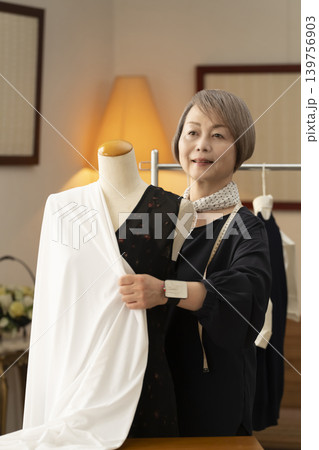 シニア女性のデザイナーがアトリエで洋服を作る シニア女性のデザイナーがアトリエで洋服を作る 139756903