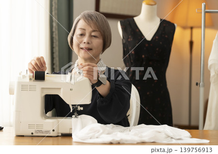 シニア女性のデザイナーがアトリエで洋服を作る シニア女性のデザイナーがアトリエで洋服を作る 139756913