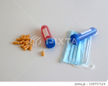 Medical composition with capsules, sample tubes and protective face mask for healthcare treatment and infectious disease concepts. Scientific scene for virus research and medical diagnostics. 139757124