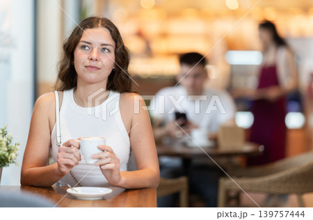 Young woman drinking coffee in cafe 139757444